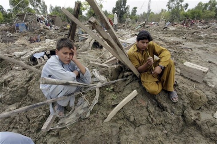 Pakistani villagers sit on their houses collapsed by floods in Nowshera, Pakistan on Thursday. Pakistani officials urged anyone left in three southern towns to evacuate immediately as floodwaters broke through a levee, endangering areas previously untouched by the country's almost monthlong disaster.